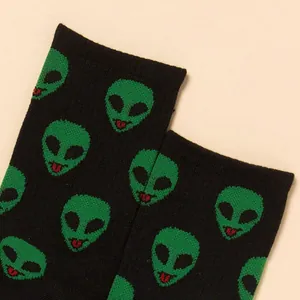 Trendy black crew socks for men featuring a repeating green alien head pattern print