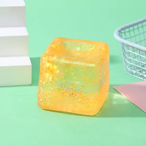 Close-up of a translucent orange glitter water cube squishy toy for stress relief