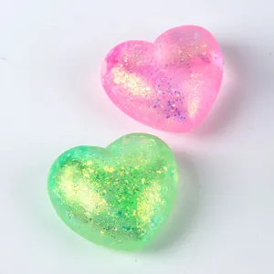 Close-up detail of pink and green heart-shaped glitter squishy toys with sparkles
