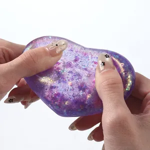 Hand squeezing a purple glitter heart-shaped maltose squeeze toy for stress relief