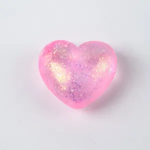 Detailed view of a pink heart-shaped squishy toy filled with shimmering colorful glitter.
