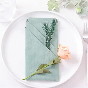 Sage green cotton linen napkin folded on a white plate for elegant festive table decor