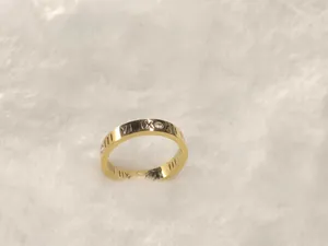 Détail d'une bague en acier titane doré avec chiffres romains et pierres brillantes