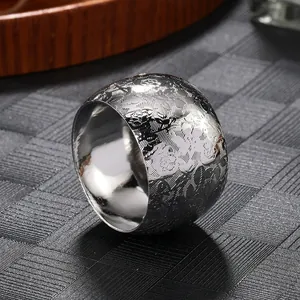 Close-up of silver metal napkin ring with engraved floral pattern for table decor.