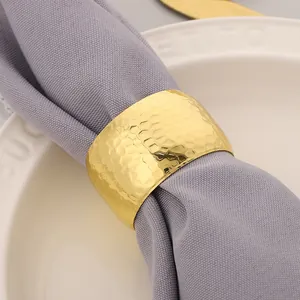 Close-up detail of a luxury golden hammered metal napkin ring on a grey cloth napkin