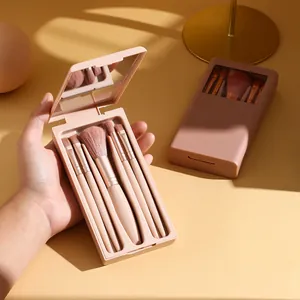Detail view of a portable 5-piece makeup brush set in a pink mirrored travel case.
