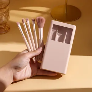 Hand holding 5-piece portable makeup brush set with a windowed pink storage case