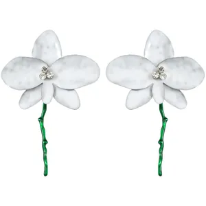 Detailed macro view of white orchid earrings featuring green stems and rhinestones