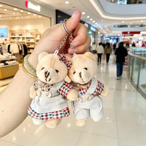Close-up of couple teddy bear keychains with linen clothes and plaid patterns.