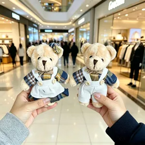 Hand holding a pair of cute teddy bear plush pendants with linen checkered outfits