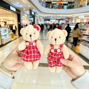A detailed close-up of two couple plush teddy bear pendants wearing red plaid outfits.