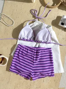 Detail of purple striped towel fabric bikini set with white cover-up shorts on sand