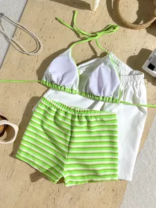 Detail view of striped terry cloth bikini set with white cover-up on sandy background.