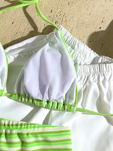 Macro view of white and neon green striped terry cloth bikini top lining and waistband.