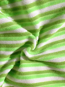 Close-up of soft green and white striped terry cloth fabric for bikini swimwear.
