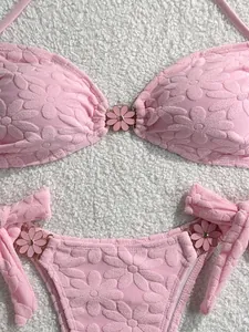 Close-up of pink floral textured bikini with cute daisy metal accents and tie side detail.