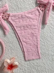 Detail of pink bikini bottom with embossed floral texture and decorative side flower.