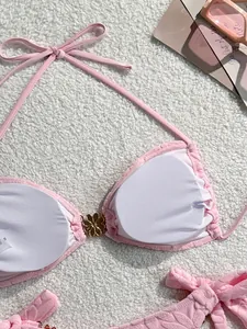 Detailed view of a pink floral bikini top featuring removable pads and a metal flower clasp