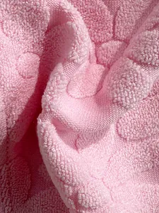 Macro view of pink textured swimwear fabric showing elegant 3D floral jacquard detail.