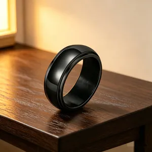 Close-up of a glossy black stainless steel spinner ring on a wooden surface