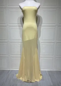 Detail view of an elegant pale yellow strapless mesh maxi dress with mermaid hem