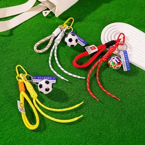 Soccer ball keychains with colorful braided rope straps on a green grass field background