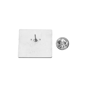 Detail showing the back view of a square metal pin with a silver butterfly clutch