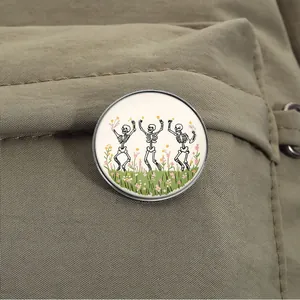 Vintage dark style round brooch with dancing skeletons and flowers on fabric background