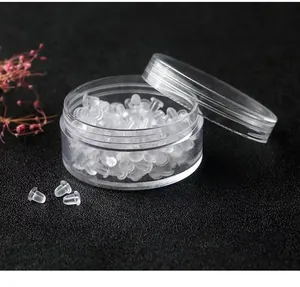 Detailed macro view of clear silicone earring backs and transparent round storage jar
