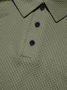 Close-up macro view of the textured waffle knit fabric on an olive green men's Polo shirt