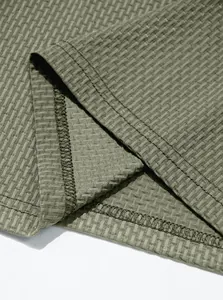 Close-up of olive green waffle knit fabric and durable double-stitched hem detail