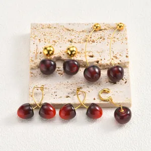 Close-up view of creative cherry-shaped stainless steel earrings with gold-plated finish