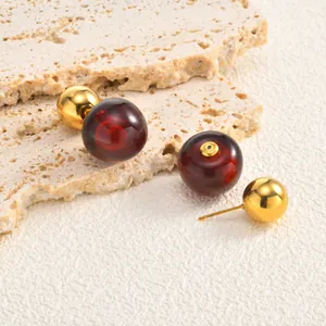 Macro view of dark red cherry-shaped earring with golden stainless steel ball