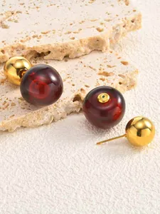 Macro detail of cherry-shaped earrings with red resin and gold stainless steel balls