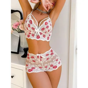 Detailaufnahme eines weißen Spitzen-Lingerie-Sets mit roten Lippen-Stickereien.