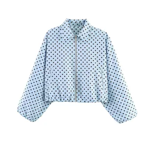 Gros plan d'une veste bleu clair à pois avec fermeture éclair et poignets élastiques