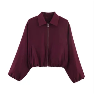 Détail d'une veste bouffante bordeaux pour femme avec une fermeture éclair argentée.