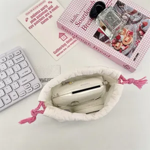 Top view of a quilted white drawstring pouch holding a Fujifilm Instax camera