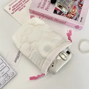 Detailed close-up shot of a cream quilted drawstring camera bag holding an Instax Mini