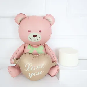 3D pink seated teddy bear foil balloon holding a gold love heart for party decor