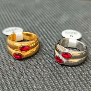 Detailed view of gold and silver titanium steel rings with oval red stones