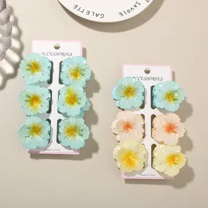 Close-up detail of colorful frangipani flower hair clips set on white display cards