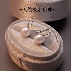 Elegant close-up of natural freshwater pearl earrings on a luxury grey velvet jewelry box