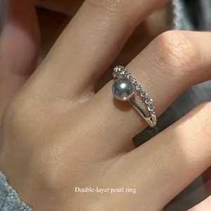 Detail of an elegant double-layered silver ring with a grey pearl and clear zircons.
