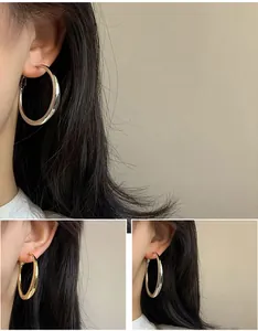 Vue détaillée de boucles d'oreilles créoles minimalistes en argent et or portées