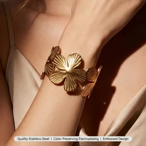 Detailed macro view of a large golden flower-shaped stainless steel open cuff bracelet