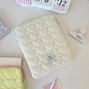 Detailed view of cream heart quilted laptop sleeve on a white minimalist work desk