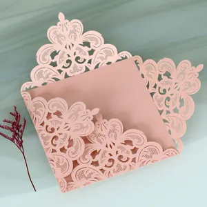 Detailed macro view of an elegant laser-cut pink wedding invitation card with intricate lace