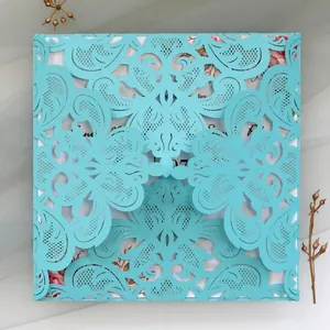 Close-up detail of a turquoise laser-cut lace wedding invitation with floral patterns.