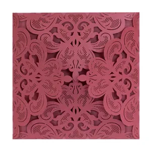 Detailed view of intricate laser-cut lace patterns on a maroon wedding invitation card